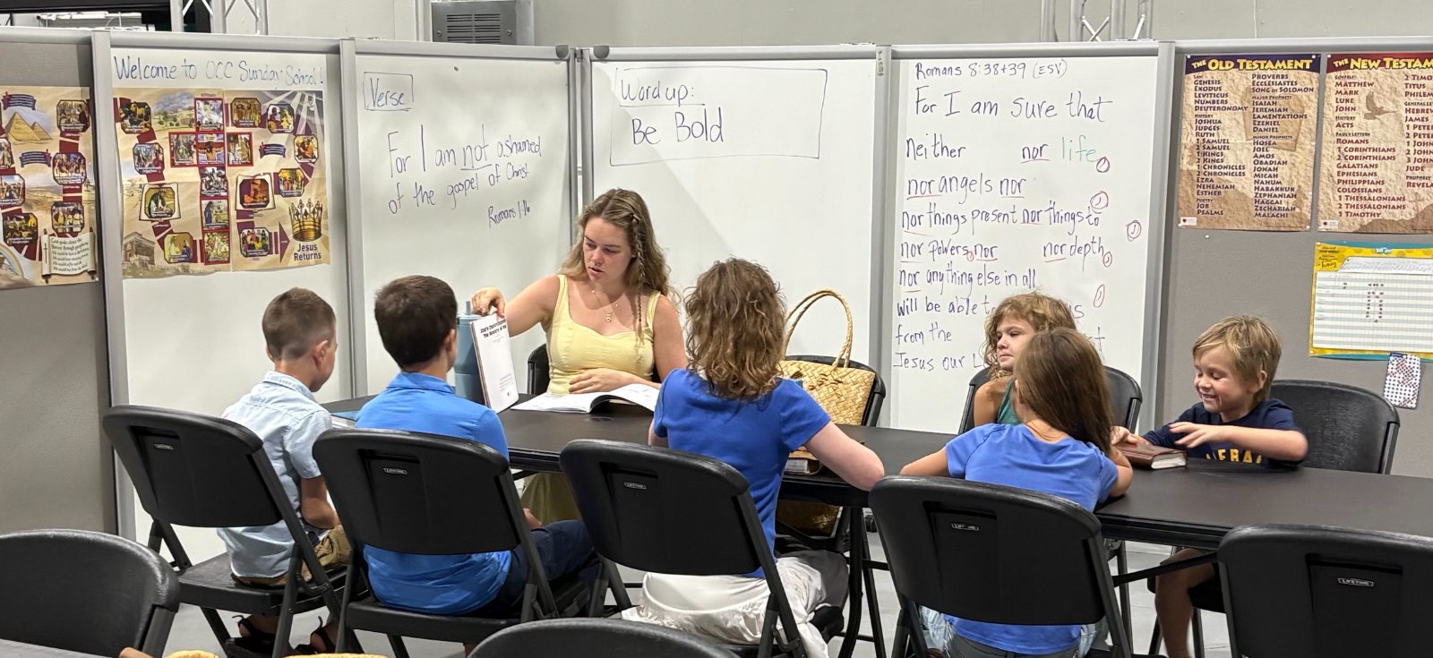 Children gathered around a table for Sunday School at Outreach Center Church, with the week's verse written on the whiteboard behind them