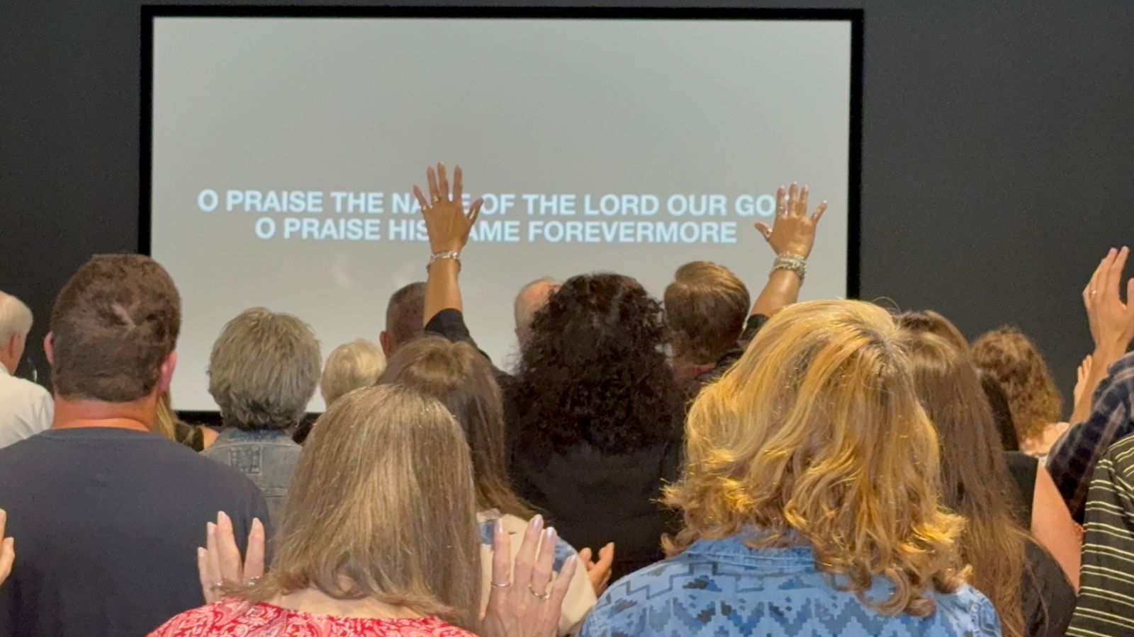 The congregation worshipping with hands raised at Outreach Center Church